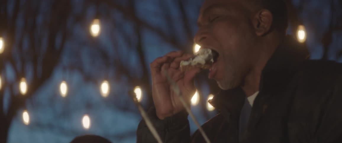 Father and son eating marshmallow at night