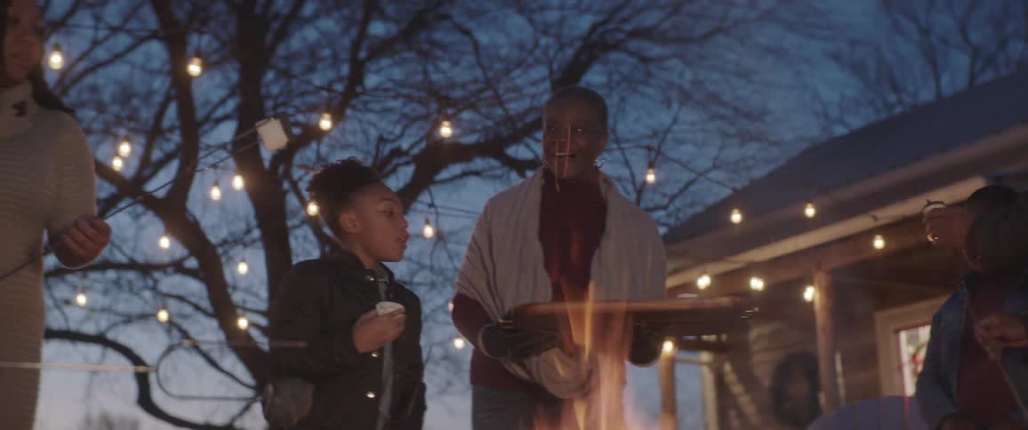 A family is making smores by a campfire in their backyard