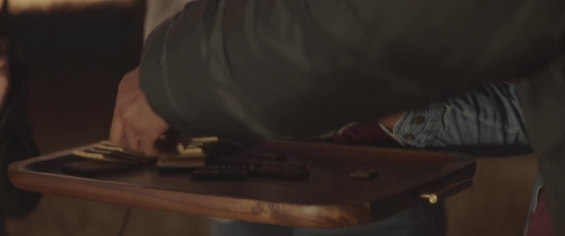 A man holds a stick with roasted marshmallows on it and his child grabs one of them