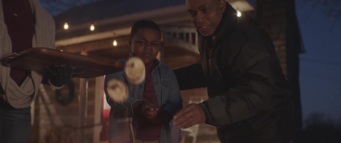 Grandparents help children roast marshmallows outside at night