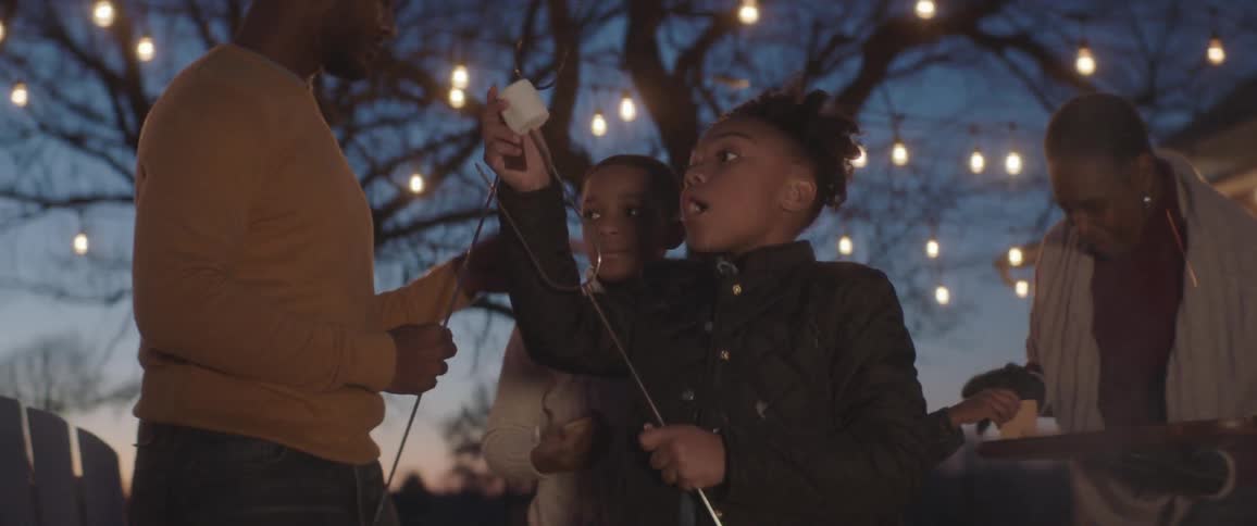A little girl puts a marshmallow on a stick to roast