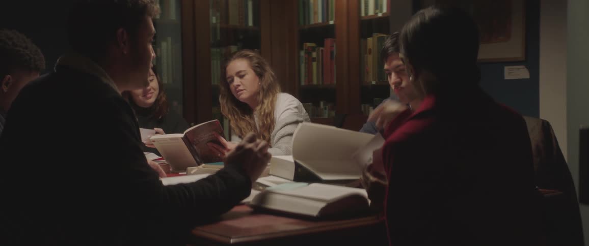 People sitting at the table browse books in the library at night