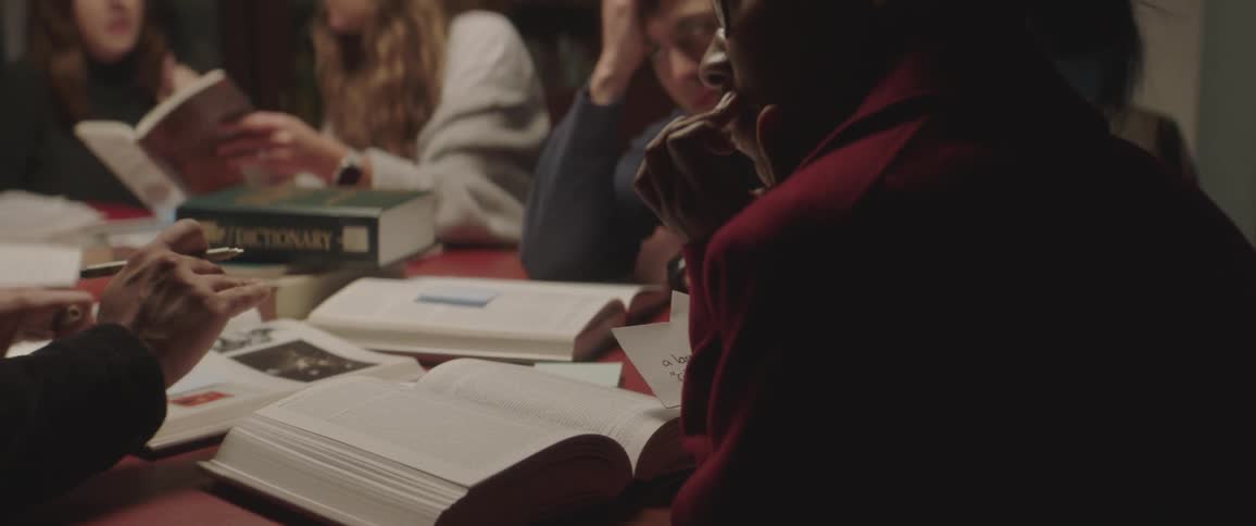 Five college students study at a table covered in open text books