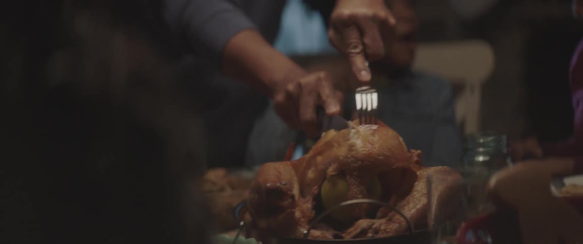 Man slices a roasted turkey with a fork and knife