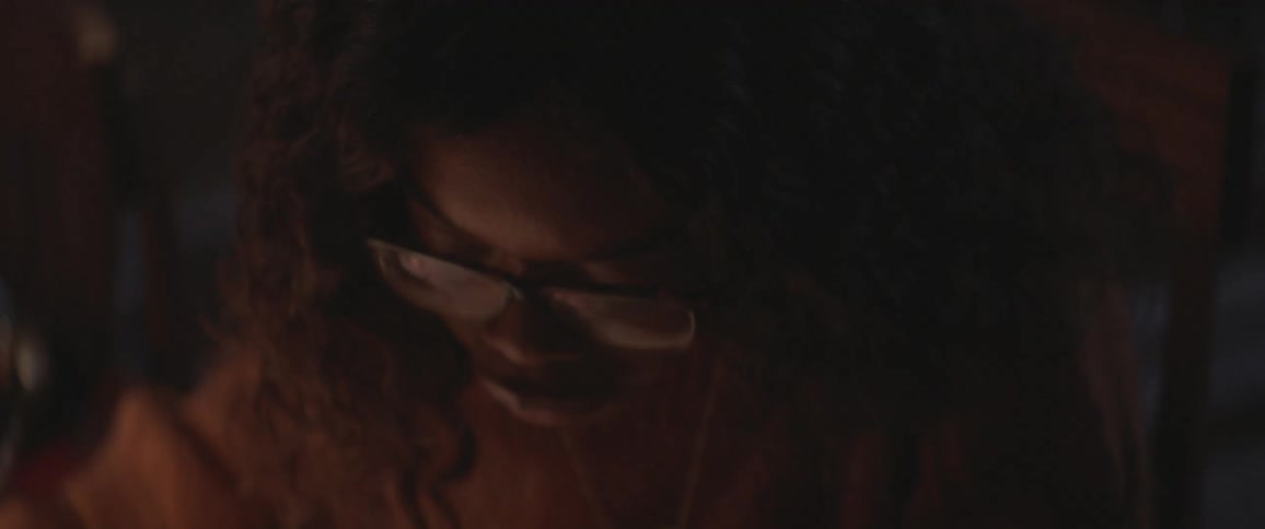 A woman writes and studies in a dark room