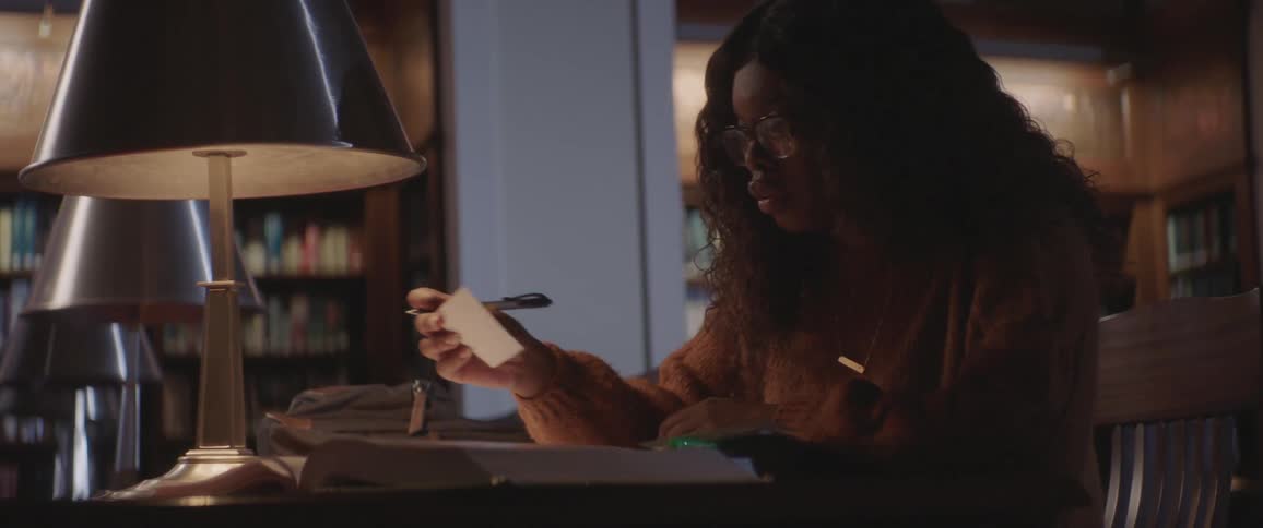 A woman sits at a desk looking at note cards