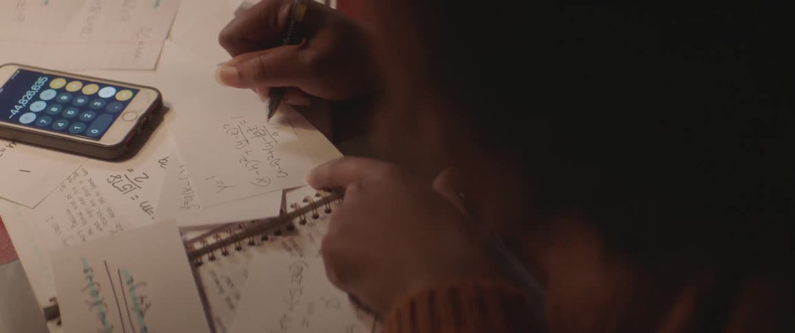 A woman is writing some calculations on paper