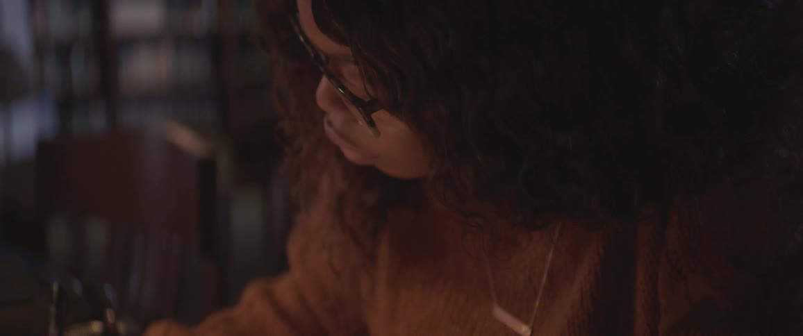 Black curly hair woman sitting at the table studies in the library at night