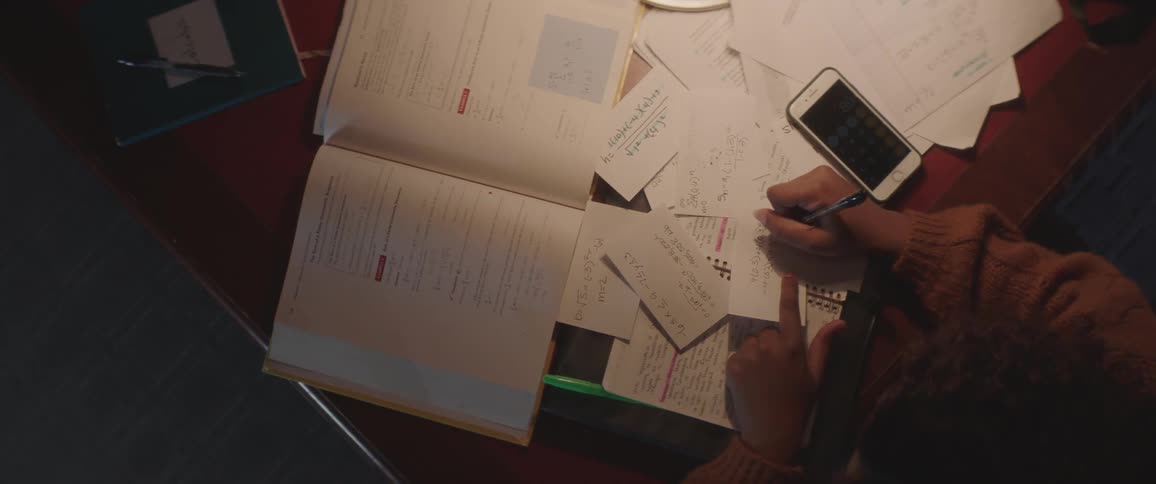 Black woman sitting at the table studies and writes down in the library at night