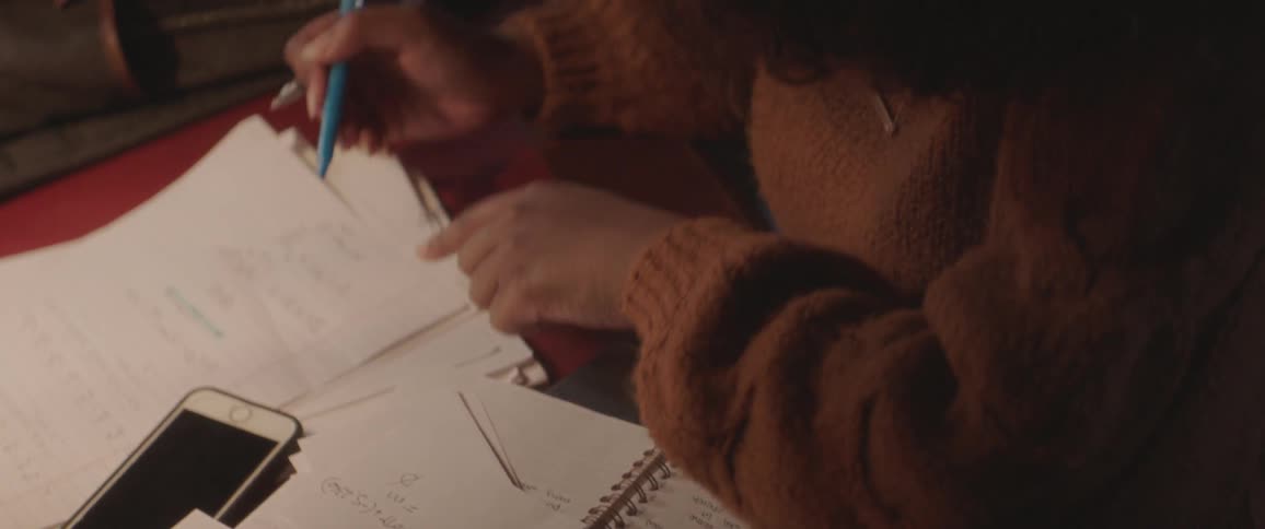 A woman studies on a desk covered with papers and notebooks