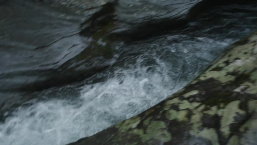 Water rushing between rocks and into a wider river