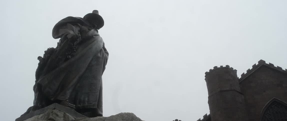 A statue of a person outside of a old stone structure
