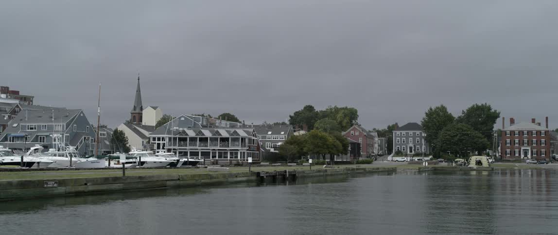 Traffic passes along road near lake and marina under cloudy sky