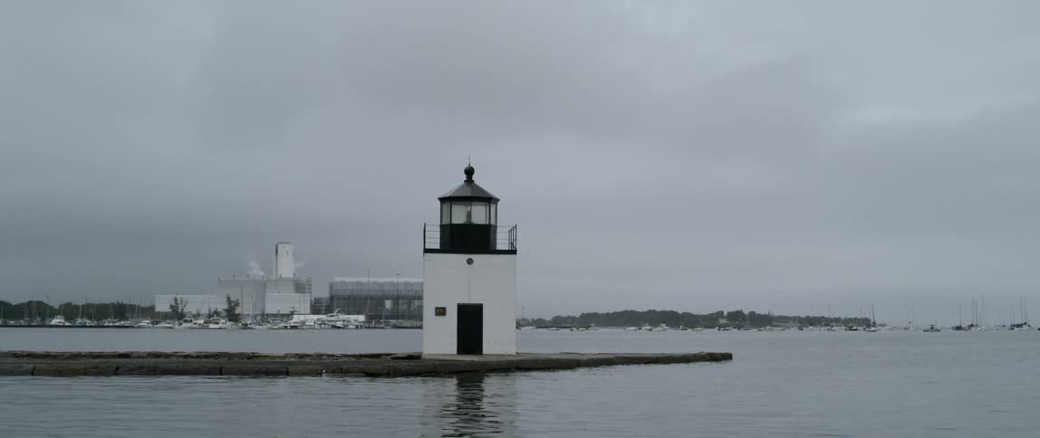 Lighthouse on low lying promontory under cloudy sky