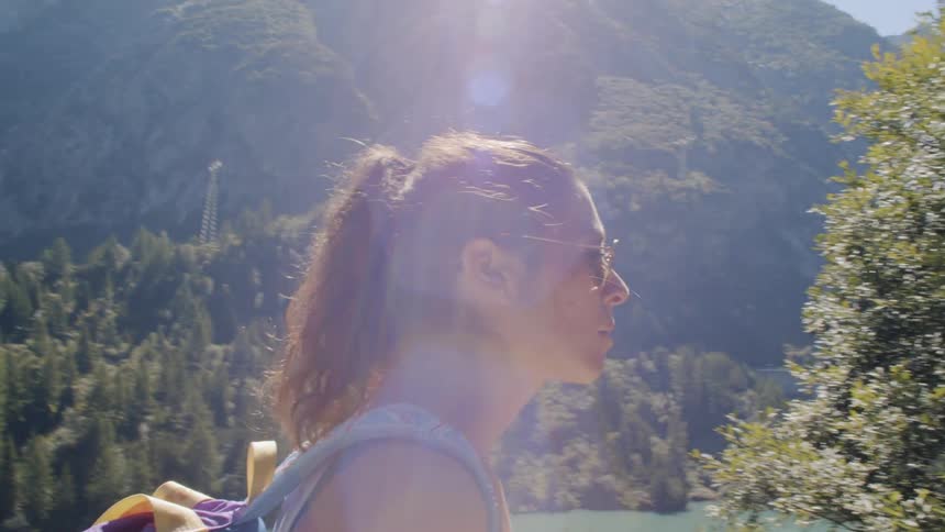 A woman is hiking near a lake in a forested area