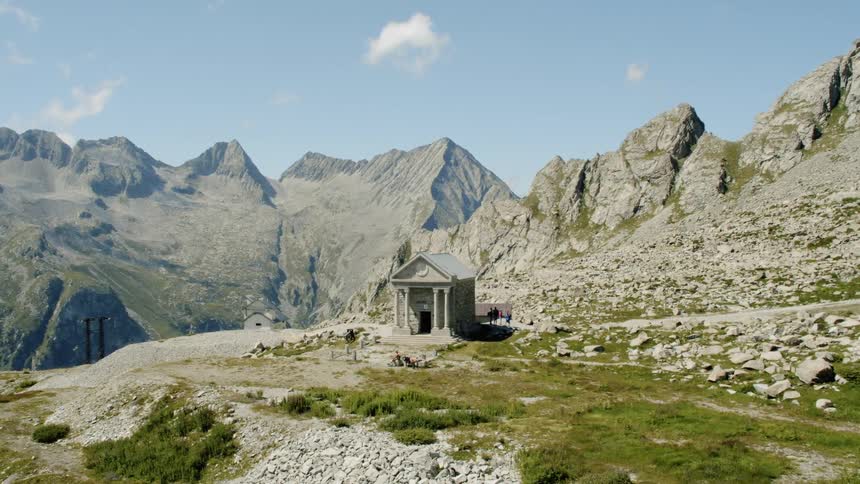 A small building sits in the middle of the mountains