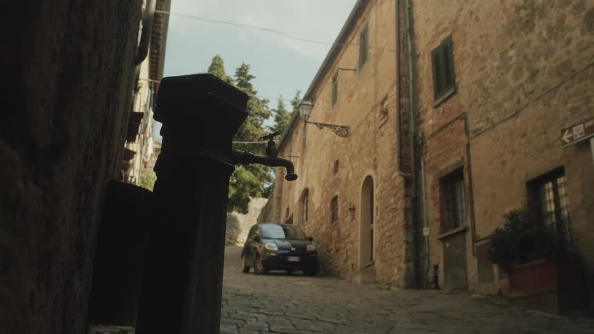 Outdoor water tap sits outside near a building and car