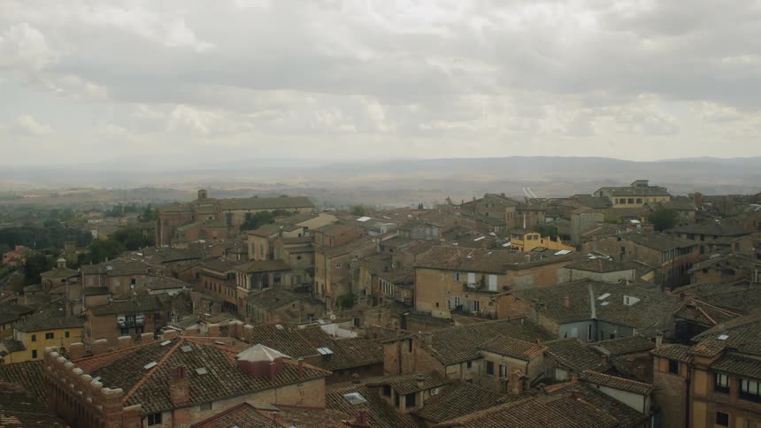 An urban area with hills in the background is visible on a cloudy day