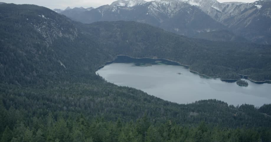A lake at the base of tree covered mountain ranges