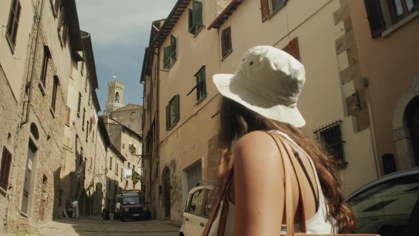 A girl stands in a street and looks around at the buildings