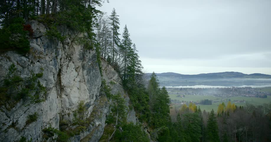 Vegetation clings to cliffside above valley