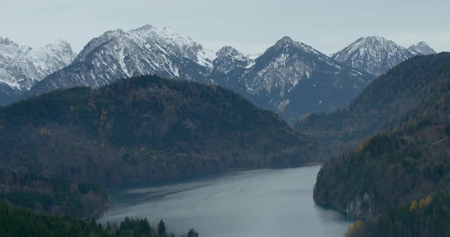 A river flows between hills with the mountains in the background