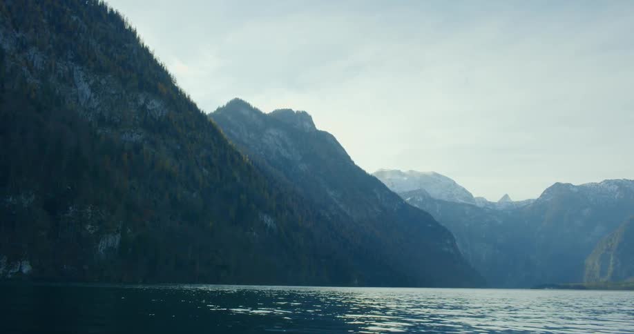 Pine tree covered mountains by a calm body of water