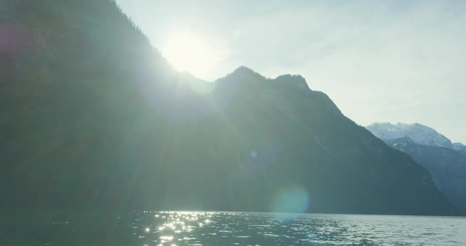 The sun reflects off a lake surrounded by mountains