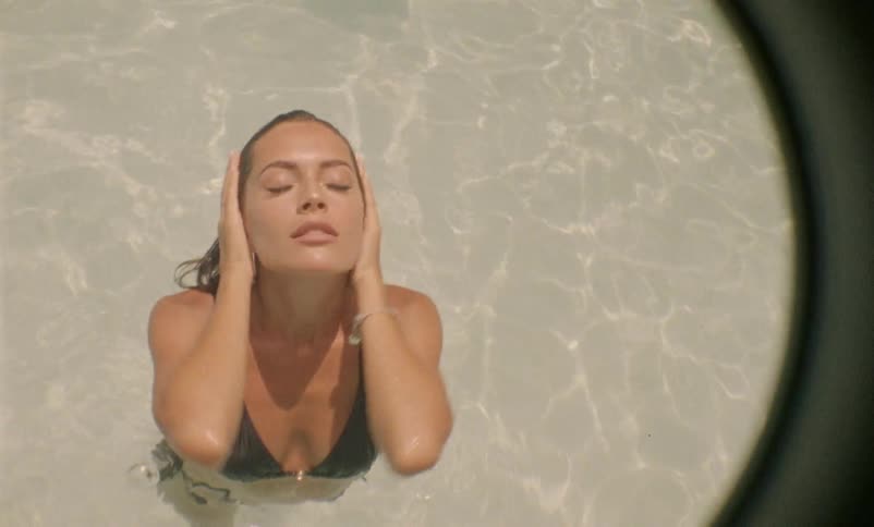 A young girl splashes water on herself in a pool