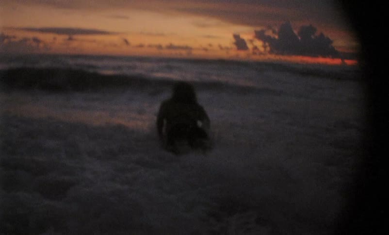 A person runs and dives onto a surfboard over a wave