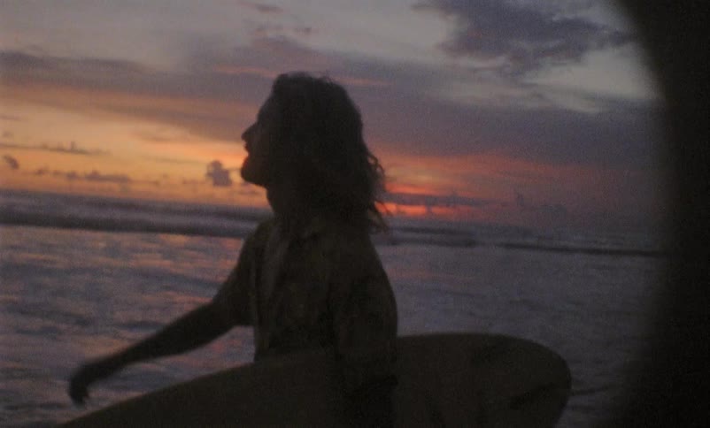 Silhouette of a male surfer holding his surfboard walking on beach at sunset