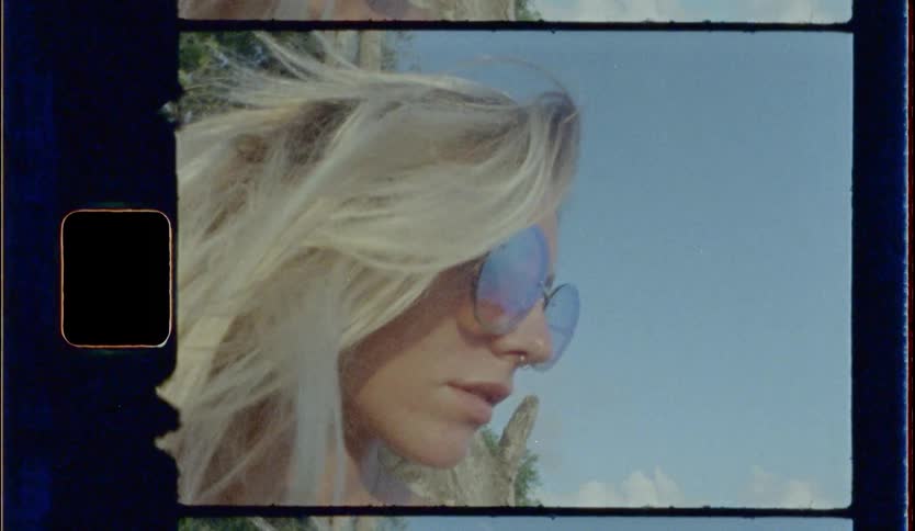 Blonde woman wearing sunglasses and nose ring looks ahead on a mountains next to a tree during daylight