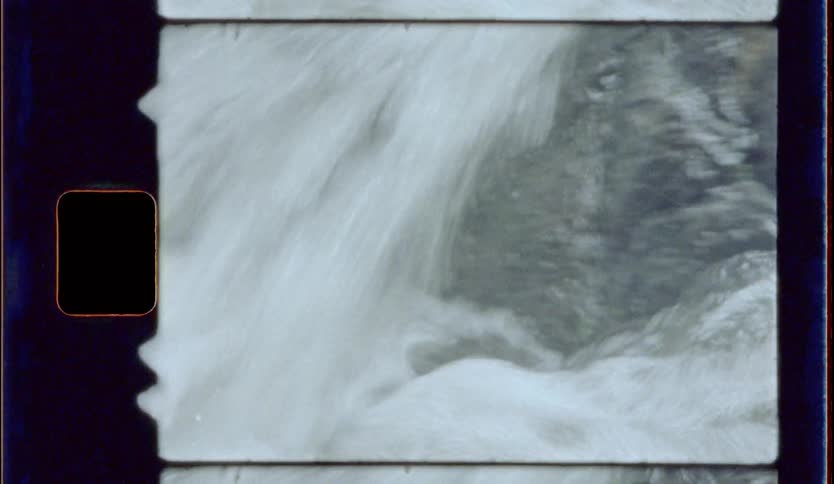 A close up shot of water rushing off of a small rocky cliff