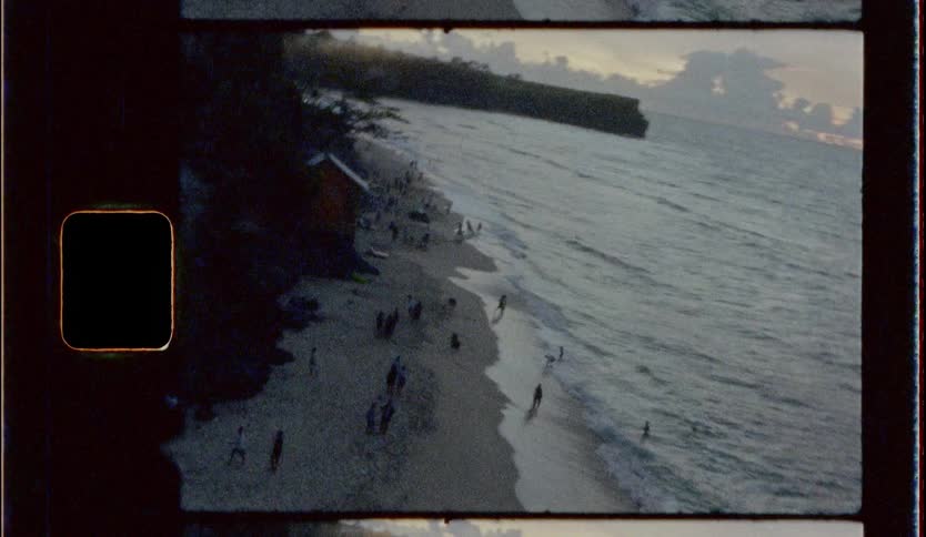 People on narrow beach between hill and ocean