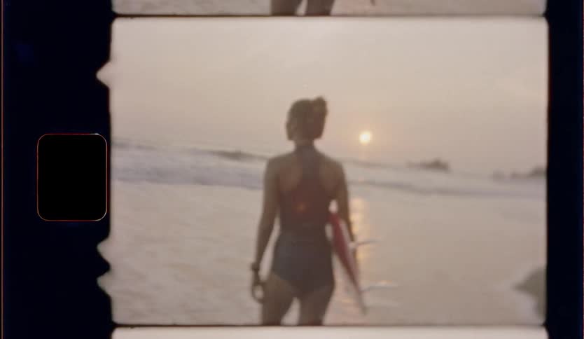 A woman carries a surfboard toward the beach