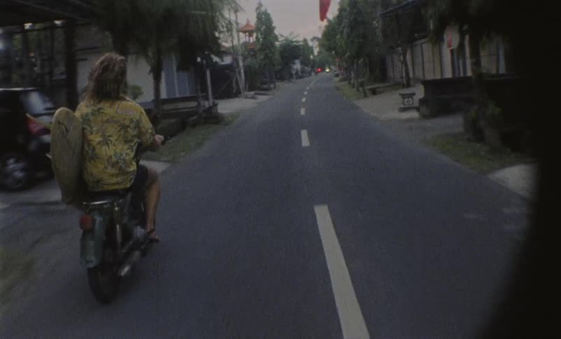 Woman rides a motorcycle down a street
