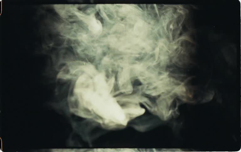 White smoke billows against a black screen in vintage film footage
