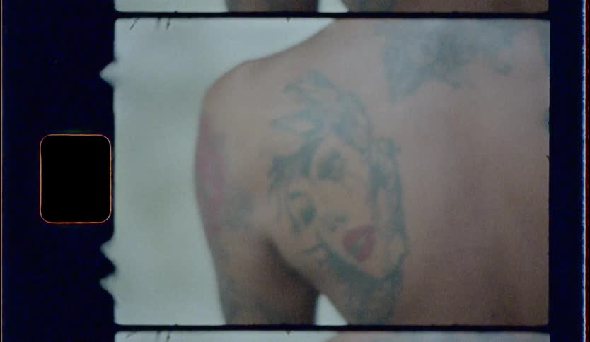 Film footage of a persons back with tattoos