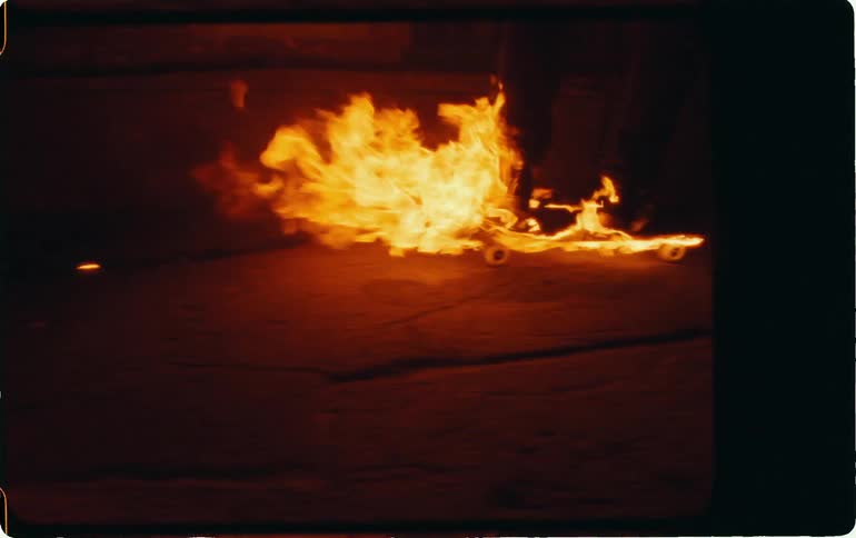 A person rides a skateboard that is engulfed in flames