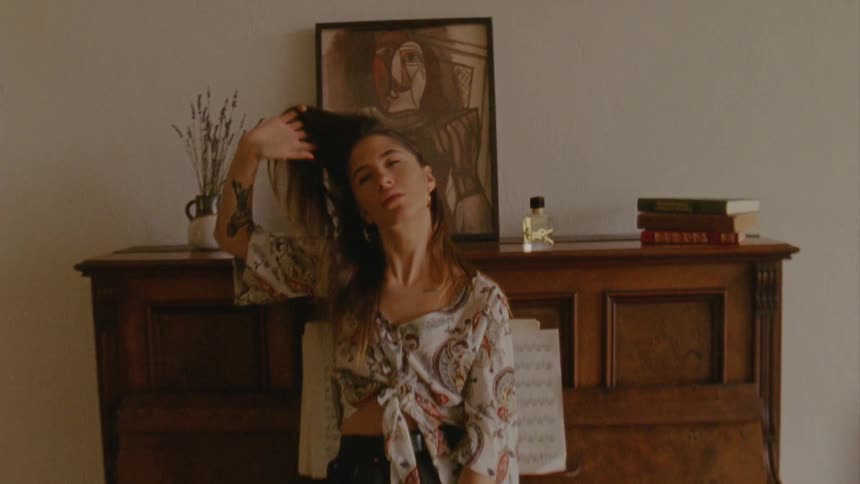 Woman sits on piano keyboard and poses for camera indoors during daylight