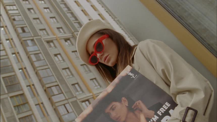 A stylishly dressed woman leaning against the corner of a building holding a dua lipa vinyl album