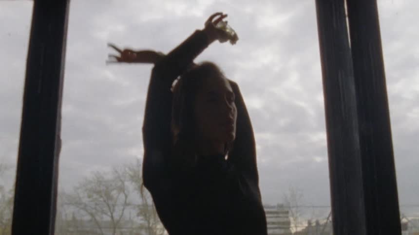 A woman doing a dance pose in front of a big glass window