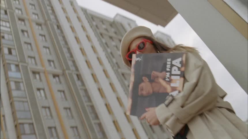 A woman modeling outside of a shop holding a poster