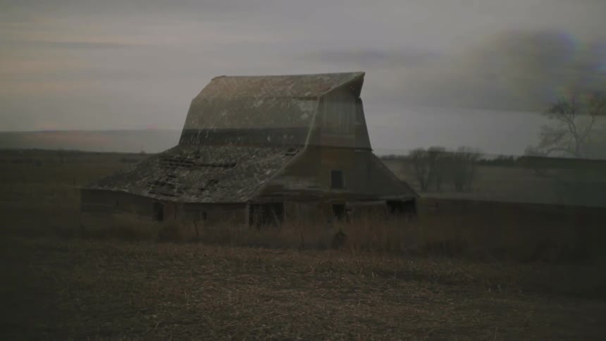 A large barn sits on a field on a cloudy day