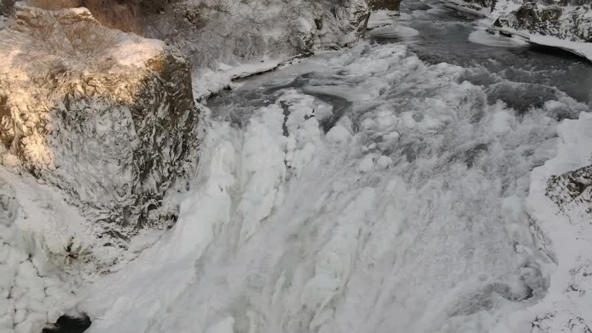 Water falls down a snow covered slope