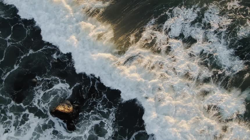 The large waves cover the rocks by the shore