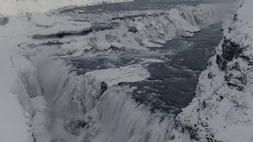 In a frozen arctic area covered in ice and snow a series of waterfalls is formed by swiftly rushing water