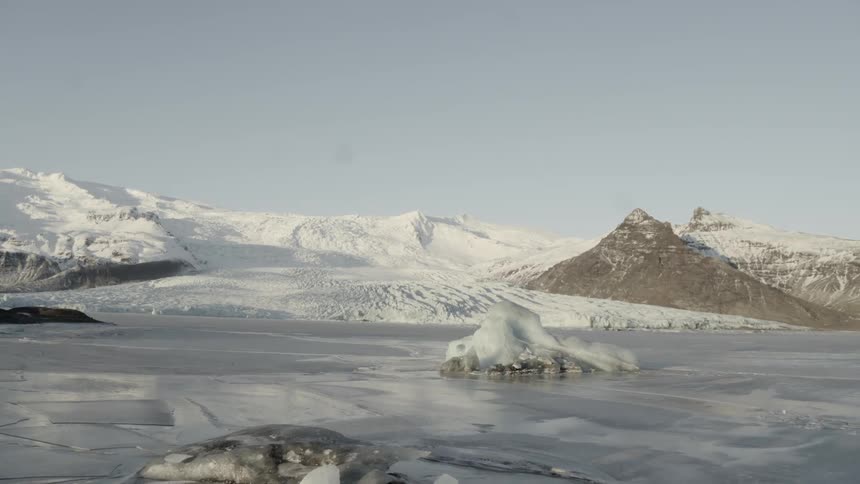 An icy lake with snowy mountains in the background