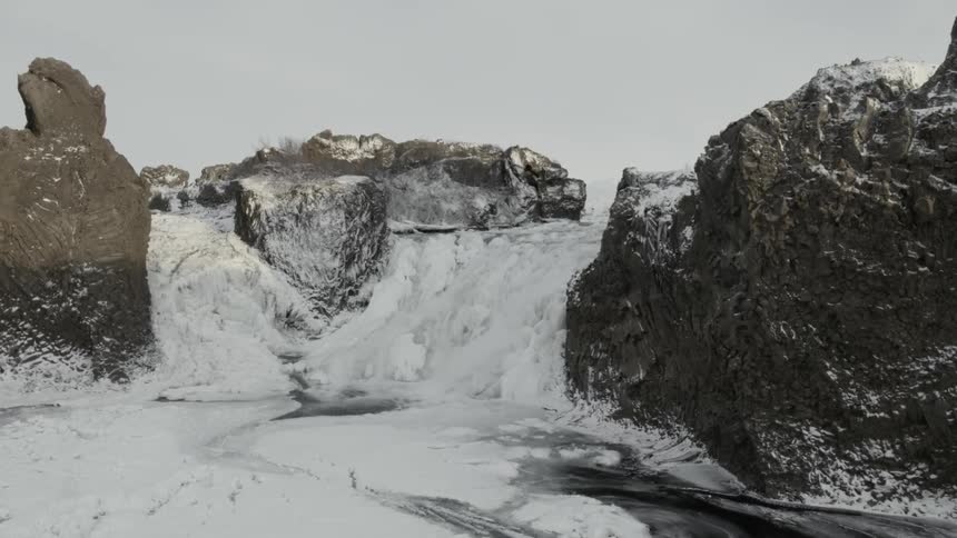 The stream runs off the cliff covered with ice