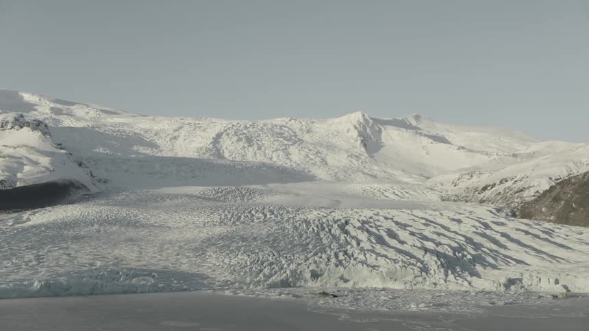 Snow covers mountains and plains under a clear blue sky